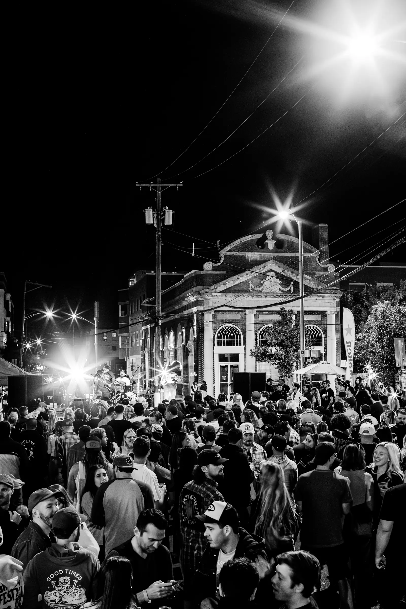 Bond Street after dark during the block party, stage lights over the crowd.