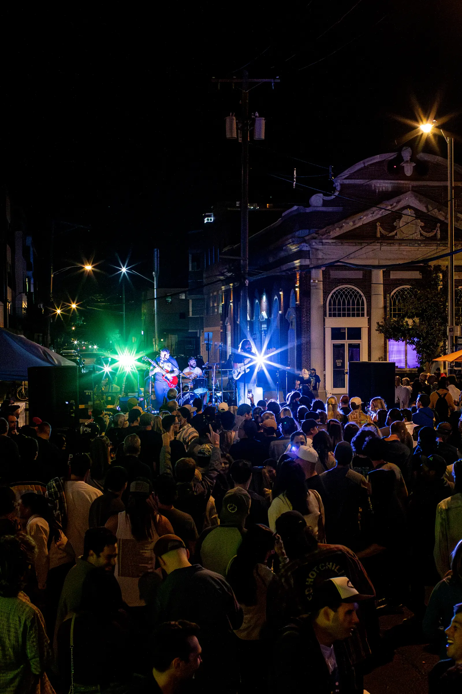 The crowd under green stage light after dark.