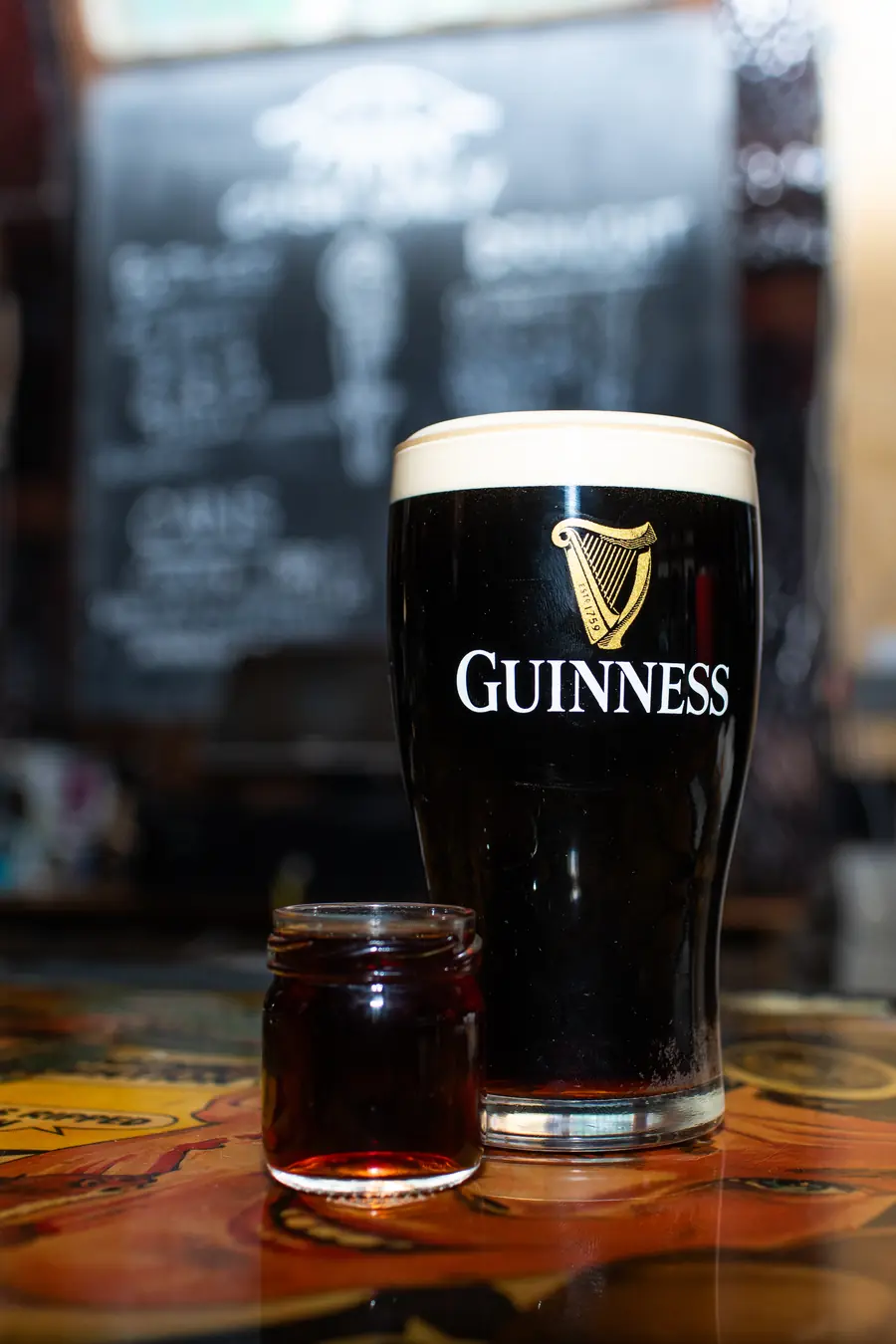 A settled pint of Guinness beside a shot jar.