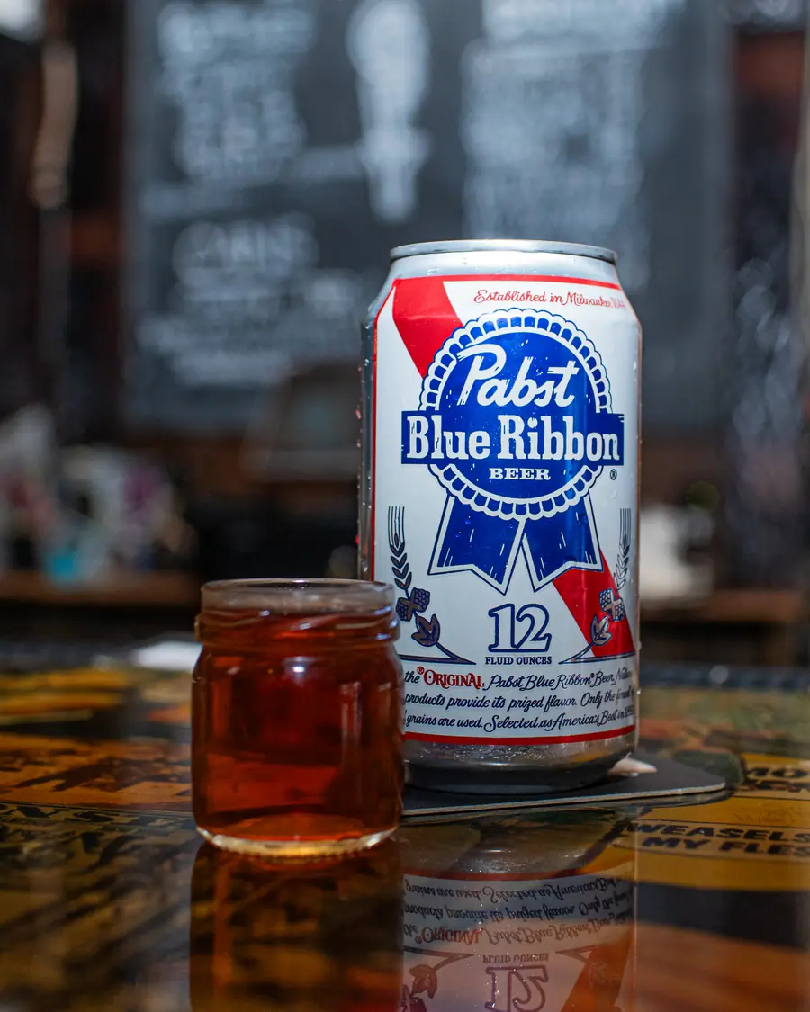 A can of Pabst Blue Ribbon beside a shot jar on the bar.